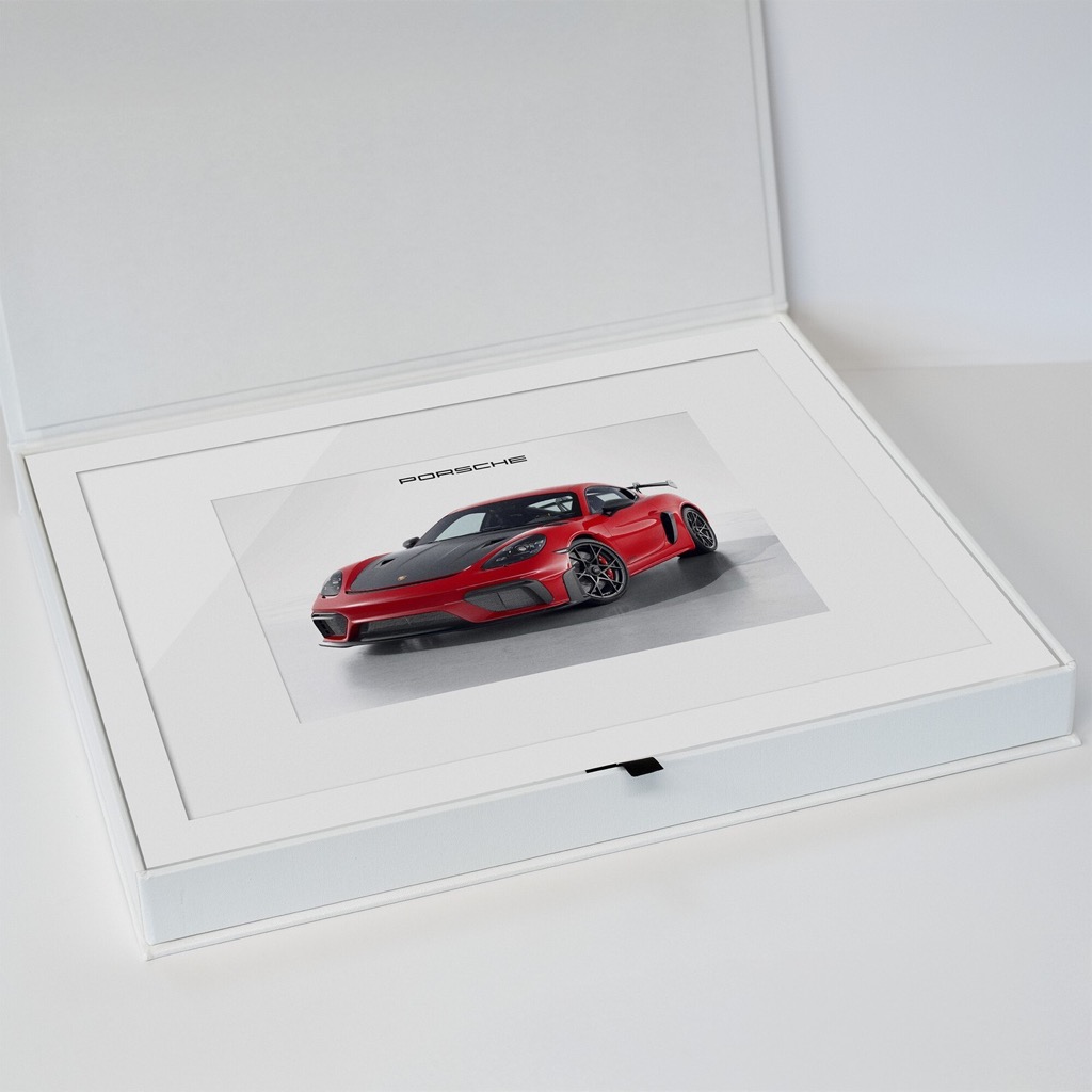 Presentation box in textured white bookcloth, opened to show a mounted print held by a locating board with a black ribbon lift.